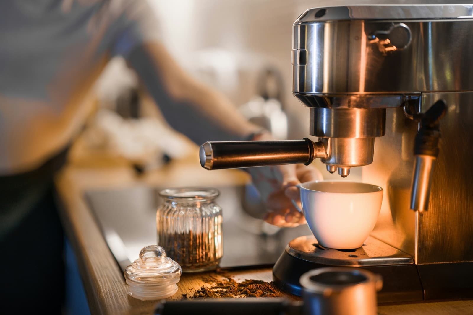 An espresso machine pulling a shot into a white cup on a wooden counter
