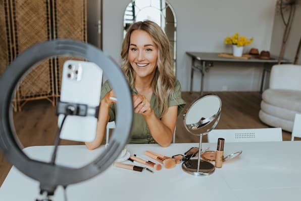 A creator filming a make-up tutorial with a phone on a ring light